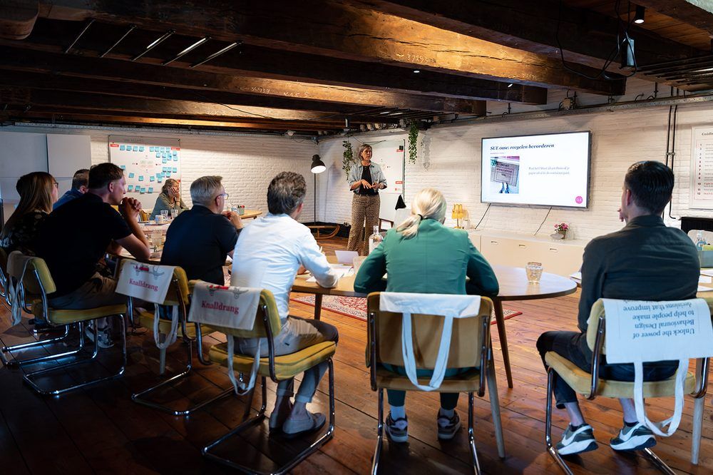 De trainingsruimte in Amsterdam met deelnemers achter hun laptops, terwijl de trainer vooraan iets toelicht.