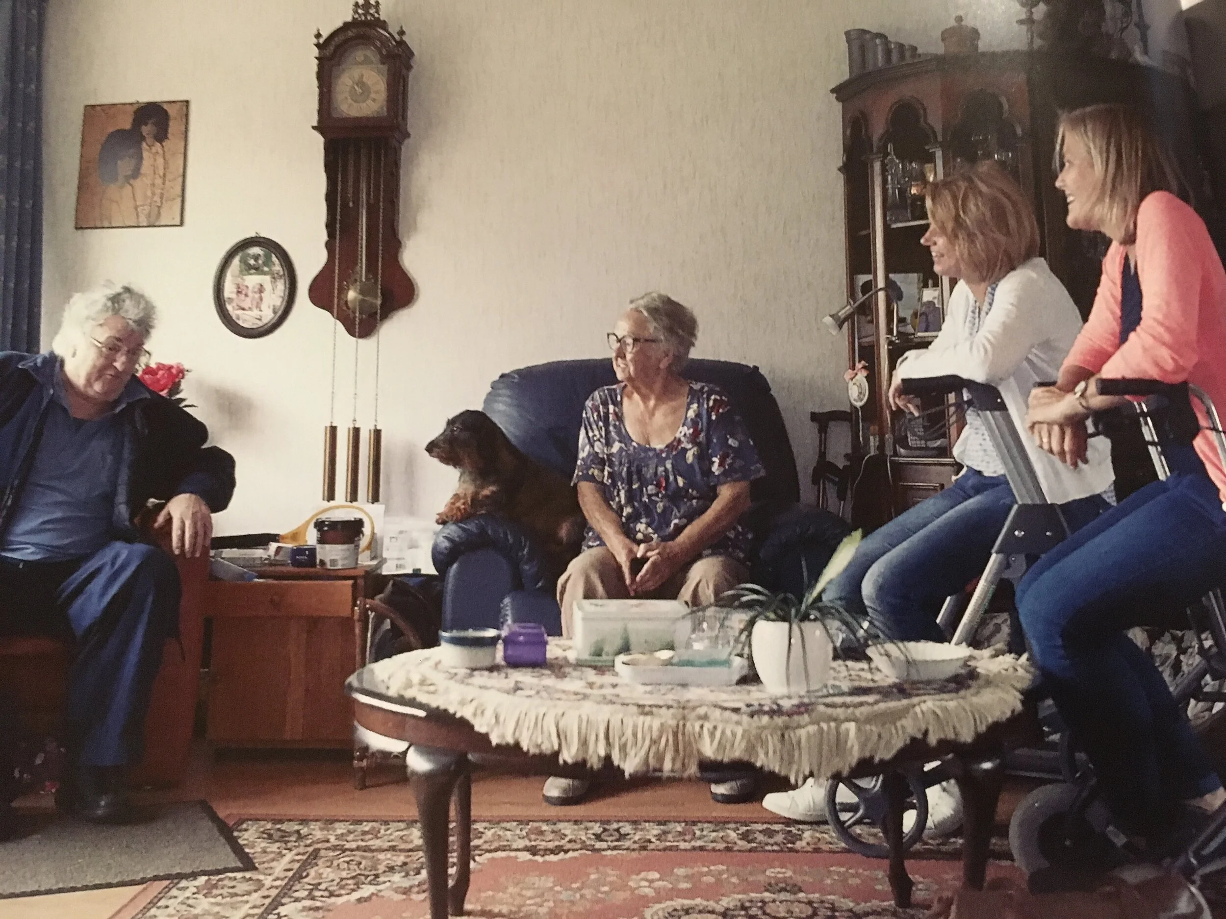 Een Buurtzorg-verpleegkundige verleent zorg aan een patiënt thuis, in een warme en persoonlijke setting