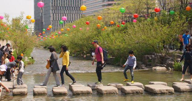 People walking along the restored Cheonggyecheon stream in Seoul — a corridor of greenery and water where a concrete motorway once stood