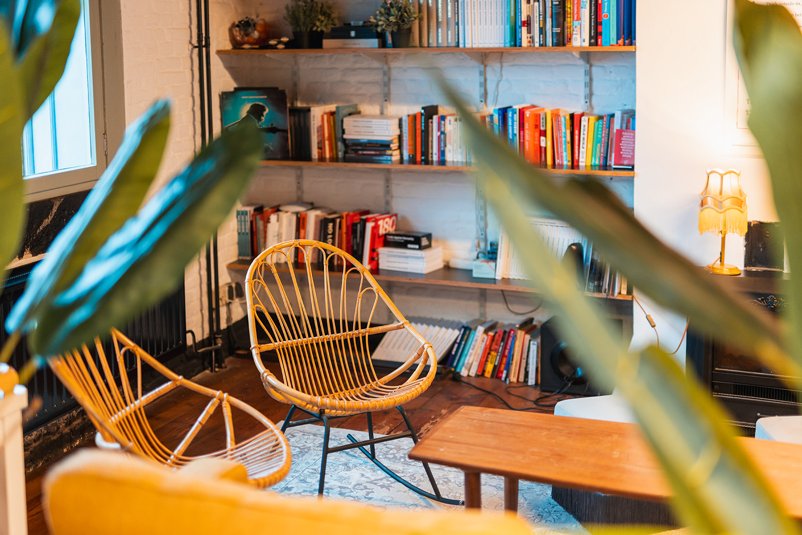 A quiet reading corner at SUE — rattan chairs, bookshelves, plants. The kind of retreat space that makes connection possible.
