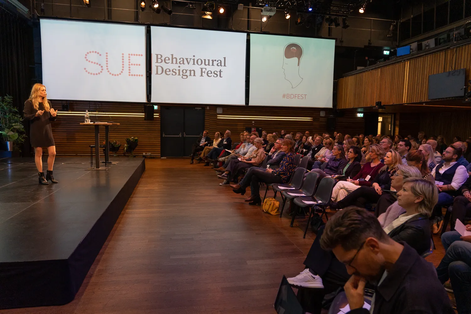 Spreker en publiek in de grote zaal van Pakhuis de Zwijger tijdens het Behavioural Design Fest