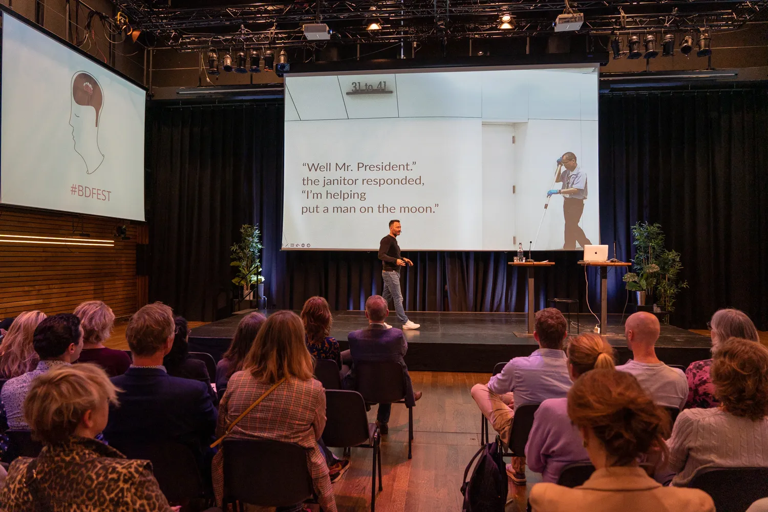 Spreker op het podium van het Behavioural Design Fest voor een aandachtig publiek