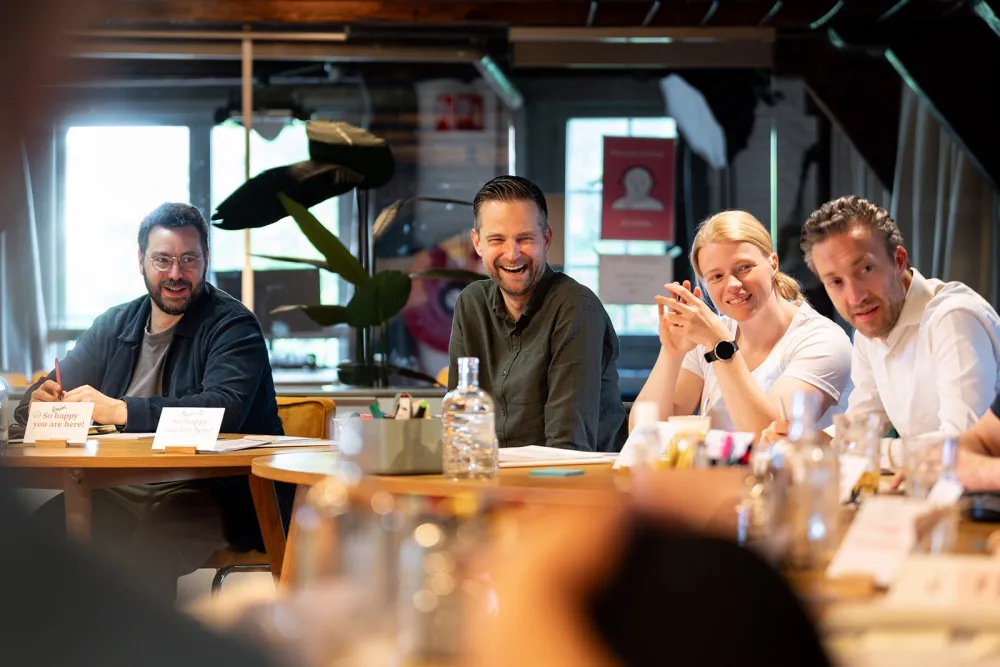 Group of participants laughing around the table during the Fundamentals Course