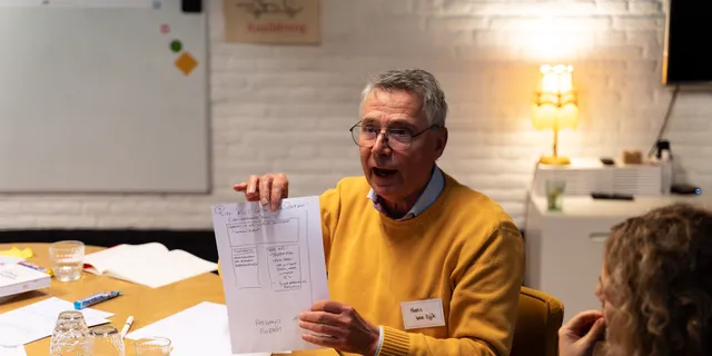 Een deelnemer laat zijn uitgewerkte werkblad zien aan de groep