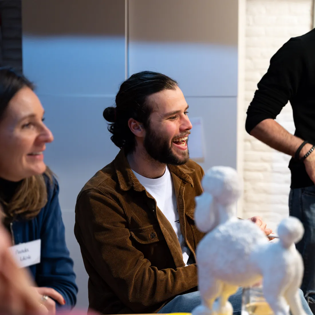 Two participants laugh at a work table during a training at SUE in Amsterdam