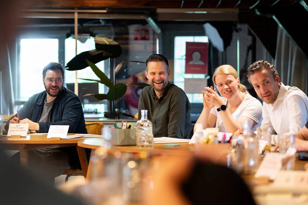 Four participants laughing at the table during a training day at the SUE building