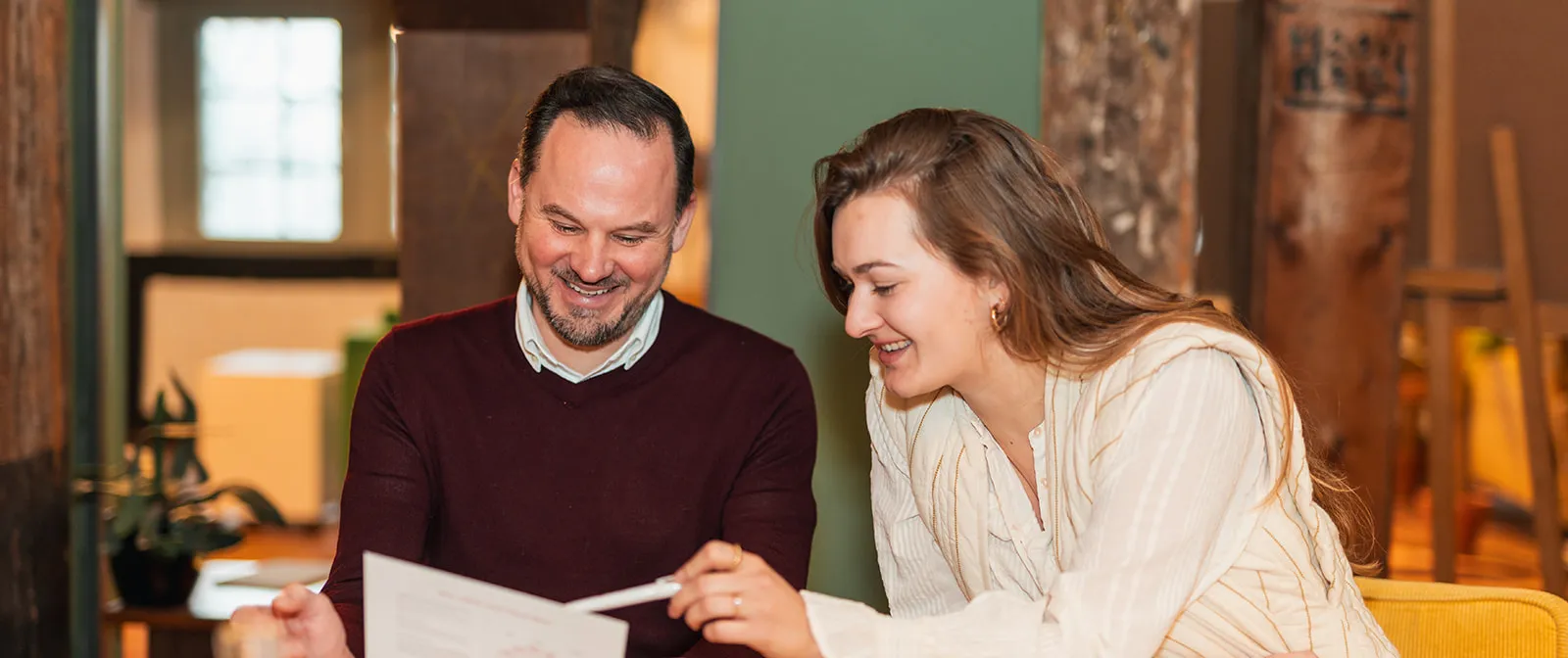 Twee mensen bekijken lachend samen een werkblad tijdens een SUE-training in Amsterdam