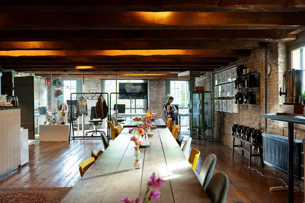 Long table with flowers and yellow chairs under wooden beams