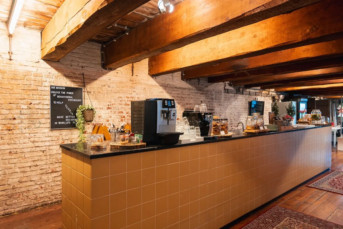 Lange koffiebar met koffiemachine en bakstenen muur