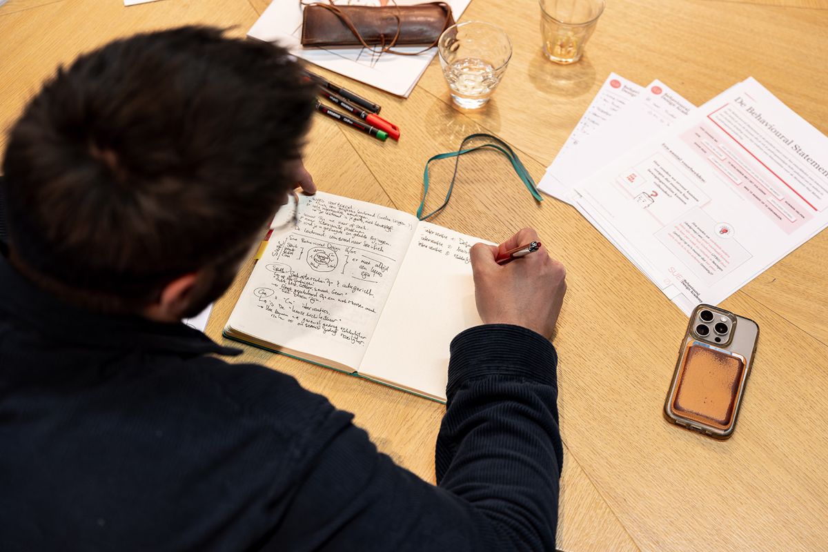 A participant writes notes next to a SUE worksheet