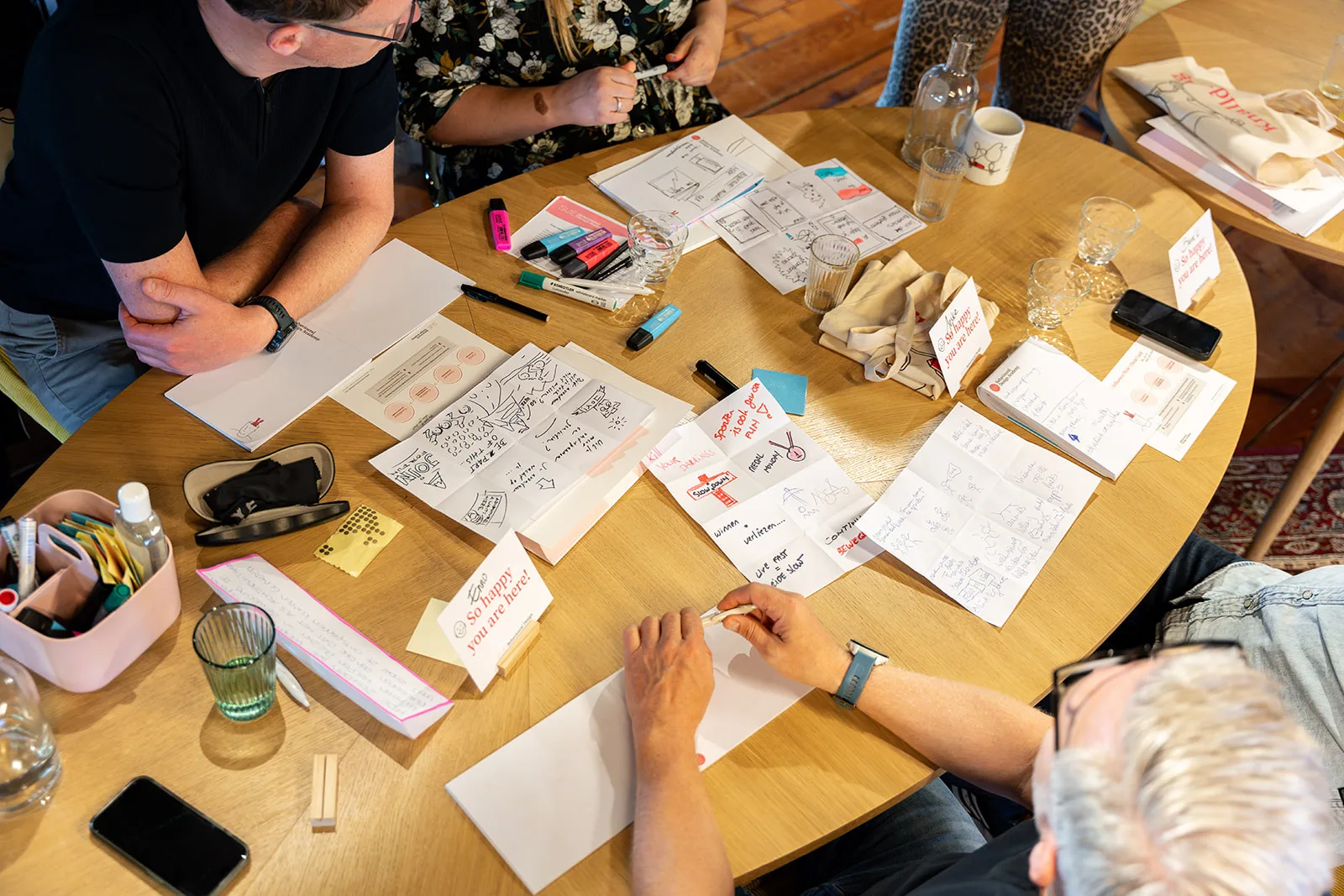 Deelnemers werken aan tafel met schetsen en werkbladen tijdens een training bij SUE Behavioural Design in Amsterdam