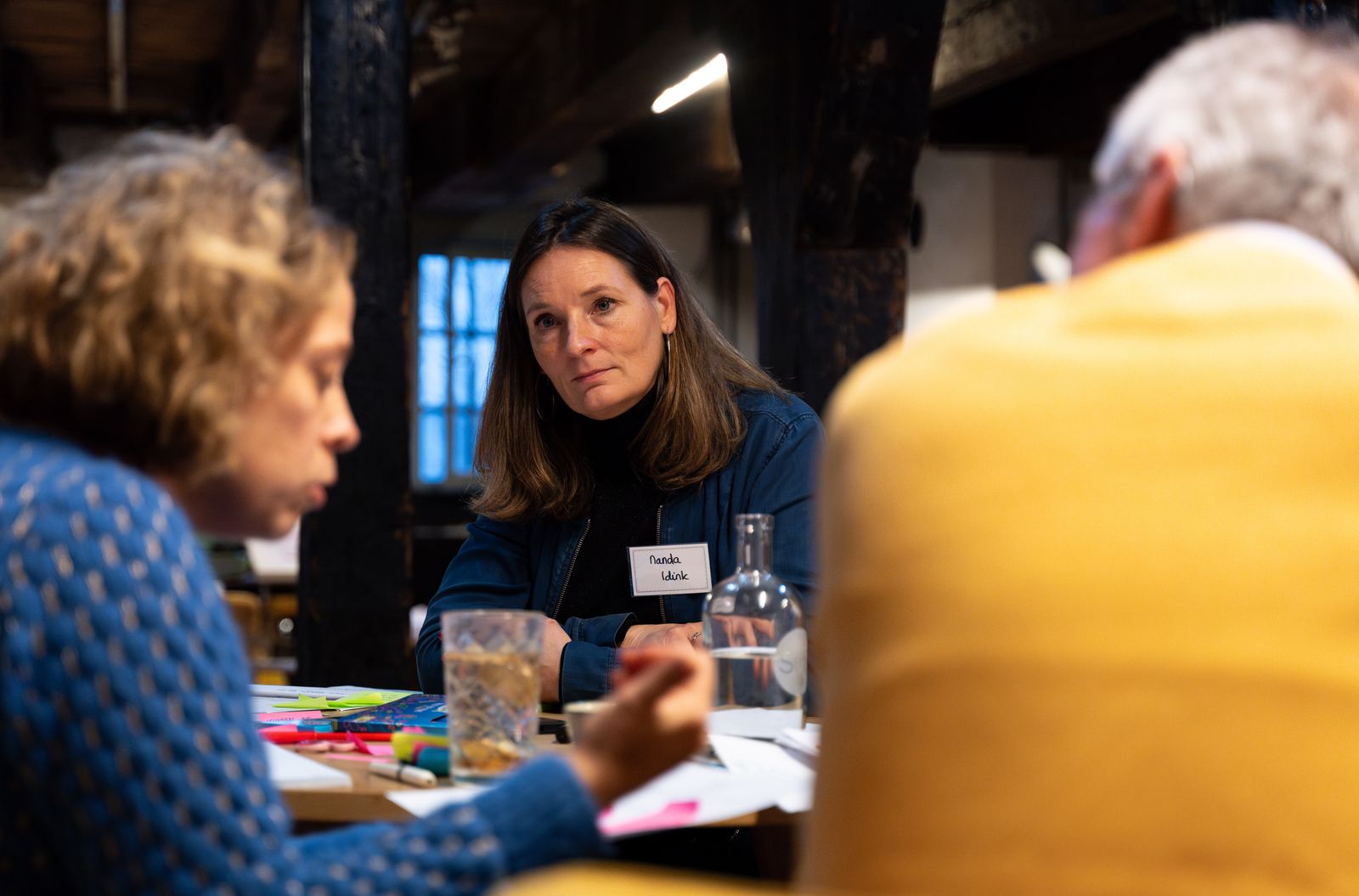 A participant listening closely to someone at her table during a session at SUE in Amsterdam