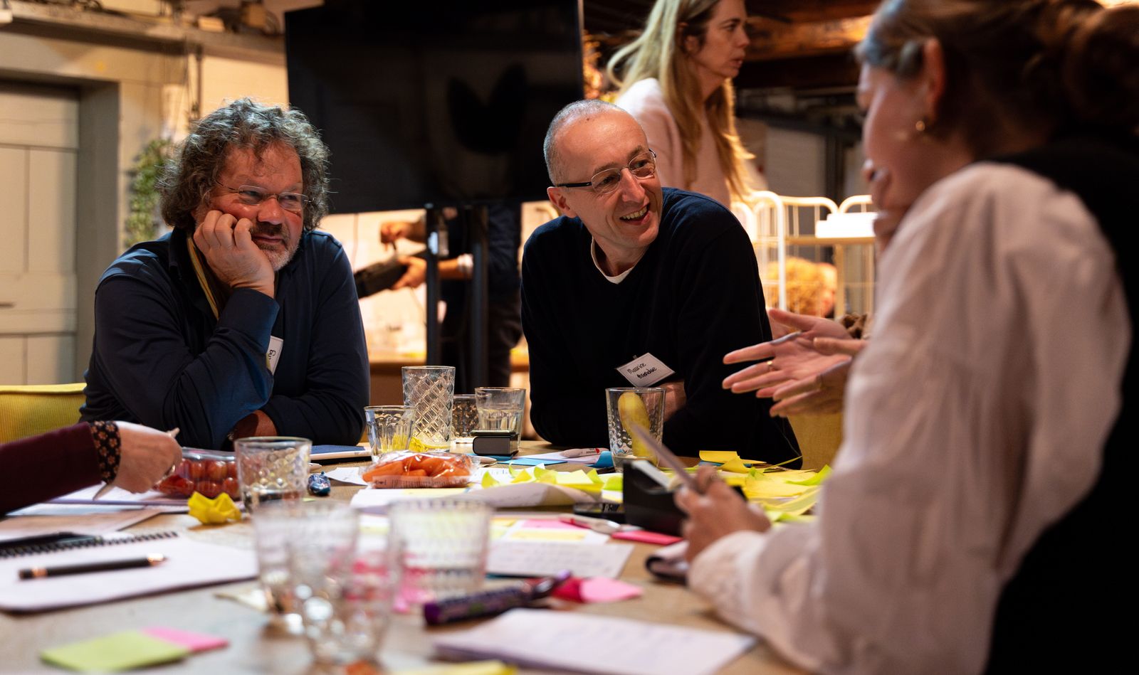 Two participants laughing at a table in conversation with a third during a session at SUE in Amsterdam