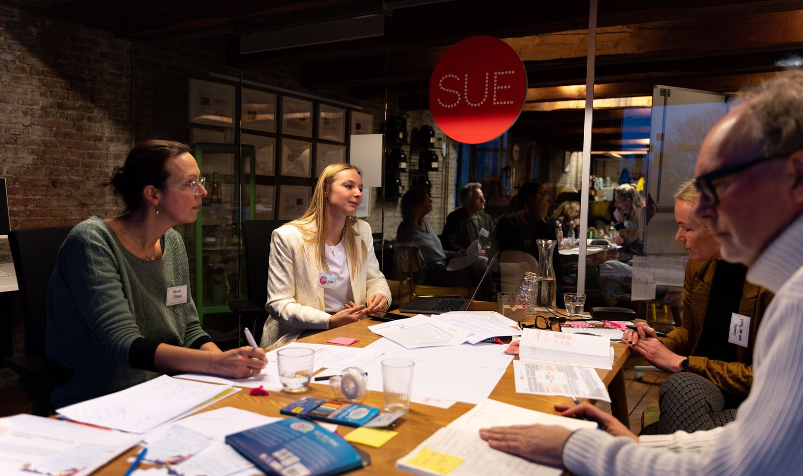 Participants in discussion at a table full of worksheets during a session at SUE in Amsterdam